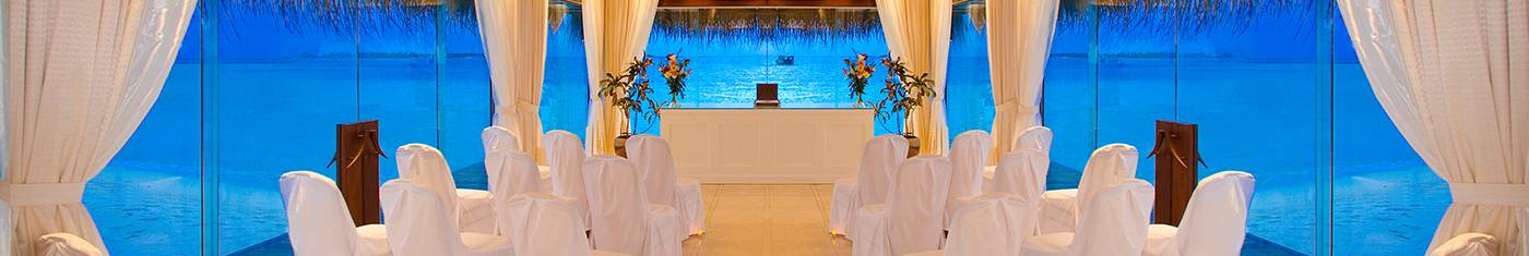 Married couple is on the beach holding their hands and the boat they came is on the shore