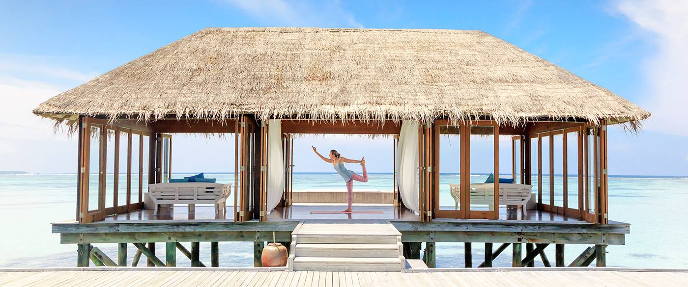 A woman posing yoga moves on Overwater villa in Maldives