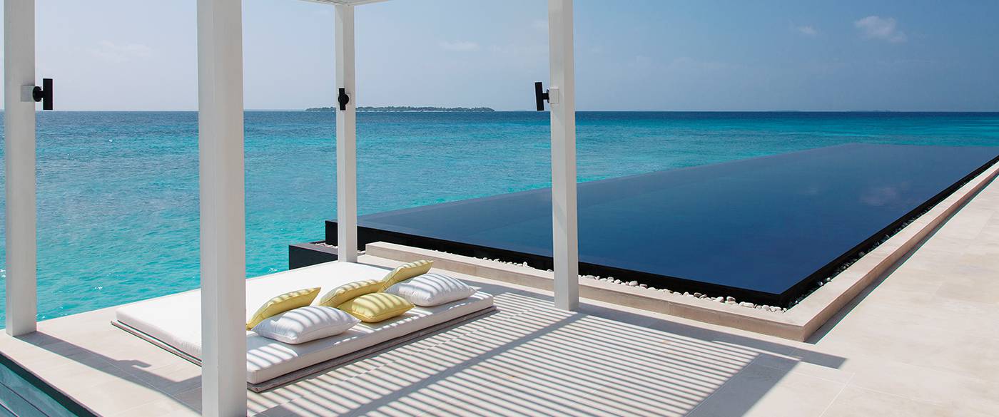outdoor view of the sun beds and infinity pool by the blue ocean