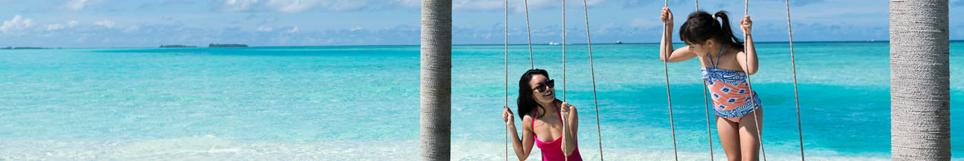 Two girls on an overwater swing enjoying their vacation